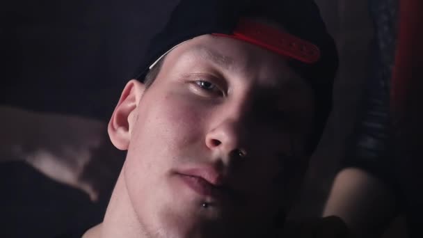 Junger Rapper mit Mütze und Gesichtstattoos vor Backsteinmauer mit Mädchen — Stockvideo