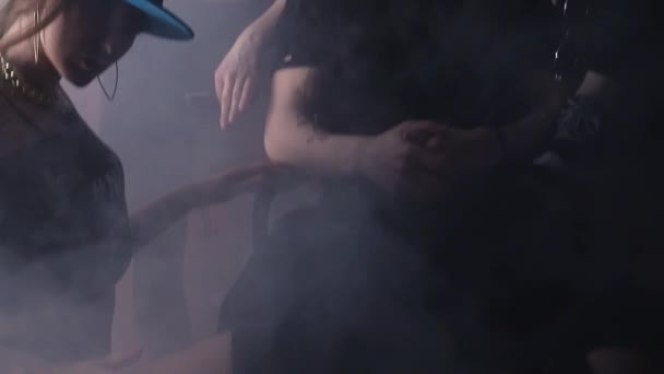 Группа сексуальных девушек окружают рэпера мужчину перед кирпичной стеной в темной комнате — стоковое видео