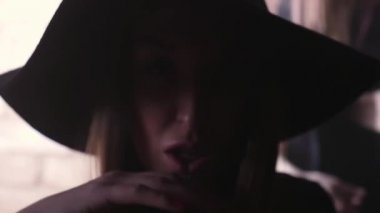 Karanlık odada, kırmızı tuğla duvar hareketleri alay şapkalı seksi genç kız