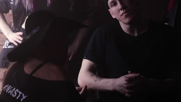 Молодой преступник в заднем ряду с татуировками перед кирпичной стеной с девушками — стоковое видео