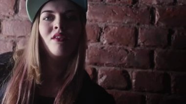 Karanlık odada tuğla duvar önünde poz hip hop snapback sarışın kız