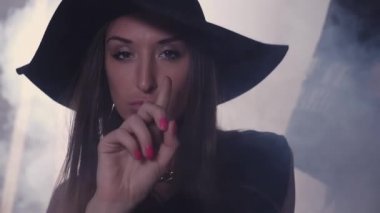 Karanlık odada, kırmızı tuğla duvar hareketleri cazip şapkalı seksi genç kız