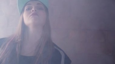 Karanlık odada tuğla duvar önünde poz rapçi snapback sarışın kız