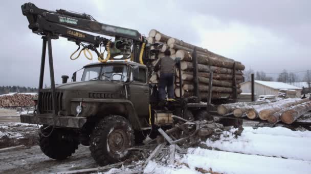 Arbetstagare klättrar på lastbil lastbil kran på dirty road på träslöjd produktion gård — Stockvideo