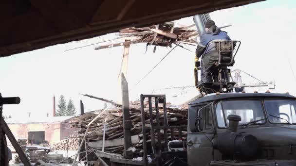 Crane dráp zavaděč uvolní zbytky dřeva od těžkých nákladních automobilů v pilařských zařízení — Stock video