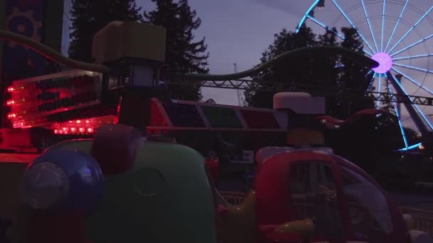 Promenade dans le parc d'attractions et roue ferris avec lumière colorée clignotante la nuit — Video