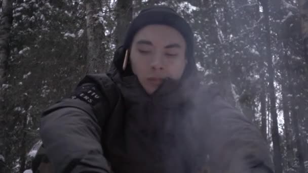 Νεαρός άνδρας κάθεται στο δάσος μπροστά από την πυρά προσκόπων καπνού με μολύβι πάνω από το αυτί — Αρχείο Βίντεο