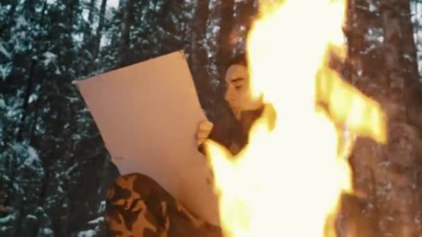 Jonge kerel tekening op doek zit op kampvuur in het bos — Stockvideo