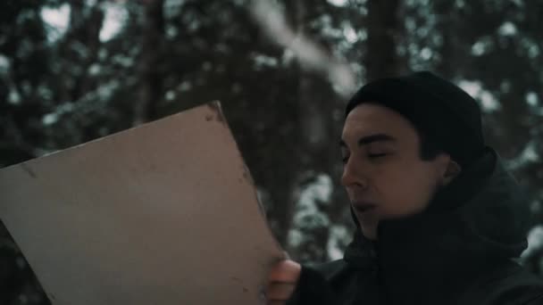 Mladý muž na plátně sedí u ohně v lese — Stock video