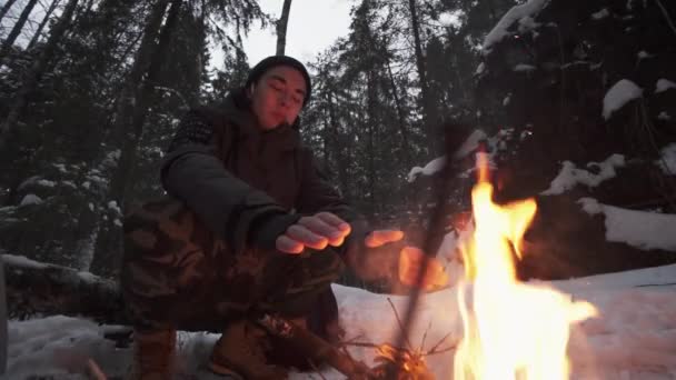 Cestovatel muž sedí v lese u ohně se snaží zahřát — Stock video