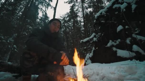 Viaggiatore uomo seduto nella foresta di fronte al falò cerca di riscaldarsi — Video Stock