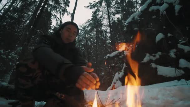 Traveler pria duduk di hutan di depan api unggun mencoba untuk menghangatkan — Stok Video