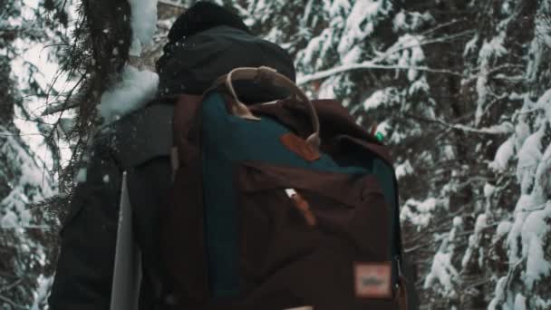 Молодой парень трогает ветку на заснеженной тропе в лесу в зимний день — стоковое видео