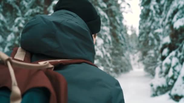Chico viajero caminando por sendero cubierto de nieve en el bosque en el día de invierno — Vídeo de stock