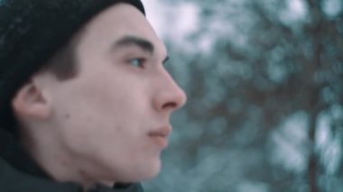 Kamera ormandaki içine sıcak giysiler içindeki genç adam görünüyor