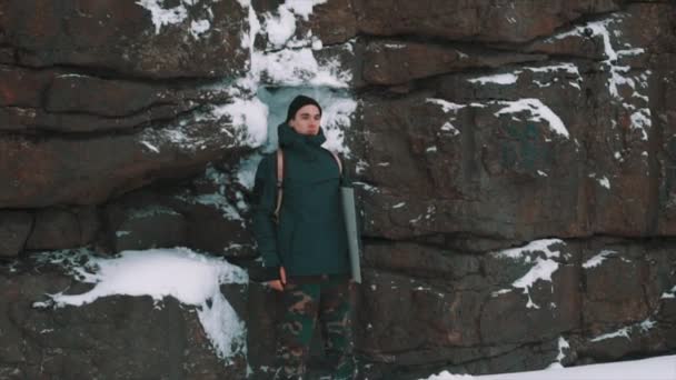 Jovem posando na frente da parede do penhasco coberto de neve — Vídeo de Stock