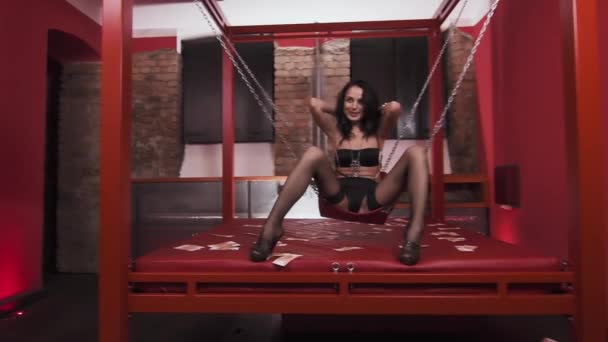 Junges sexy Mädchen in schwarzer Unterwäsche lacht auf erotischem, angekettetem Schaukelstuhl — Stockvideo