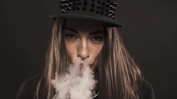 Jeune fille attrayante en pointes capuchon snapback souffle vape fumée sur le nez — Video