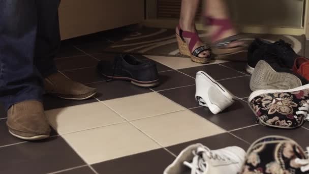 Vrouw voeten in sandalen kicks stapels van schoenen in de hal van het appartement — Stockvideo