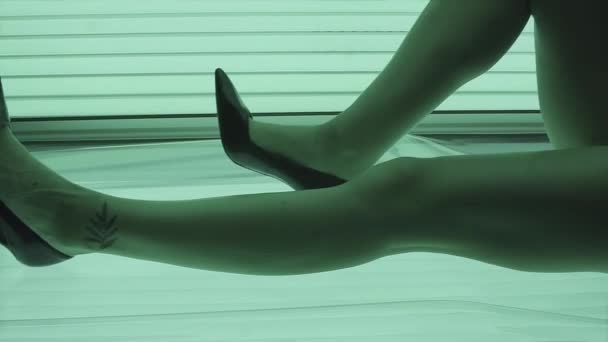 Attrractive young girl in swimsuit and high heels lying in solarium — Stock Video