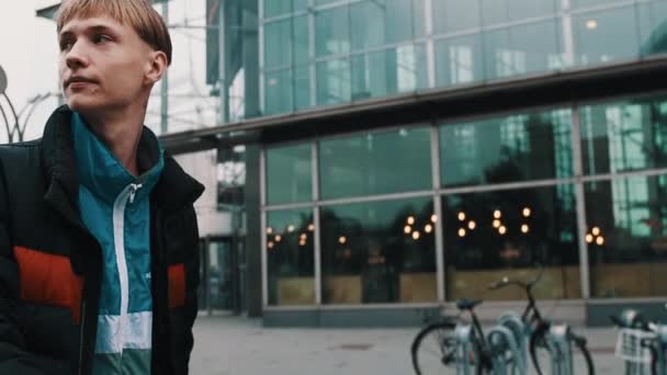 ビジネス街の建物に沿って歩くの入れ墨をしたスタイリッシュな若い男 — ストック動画