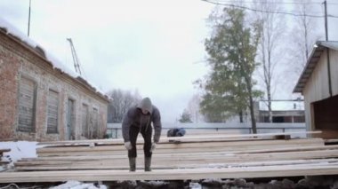 Ahşap tahta kereste fabrikası fabrika bahçesinde kış gününde taşıyan işçi