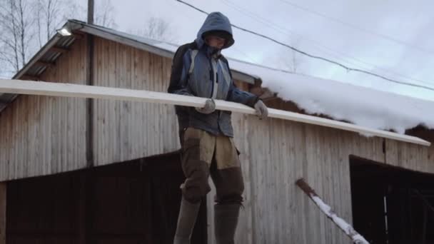 Porter carrying wood plank at sawmill factory yard on winter day — Stock Video