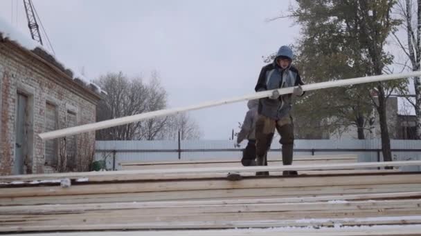 Porter que lleva el tablero de madera en el patio de la fábrica del aserradero en el día de invierno — Vídeo de stock