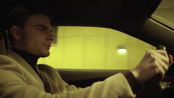 Jeune homme d'affaires satisfait conduisant une voiture dans un tunnel souterrain — Video
