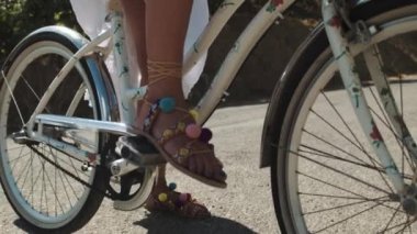 Renkli sandalet başlangıç yolu üzerinde bisiklet sürme içinde genç kadın ayakları