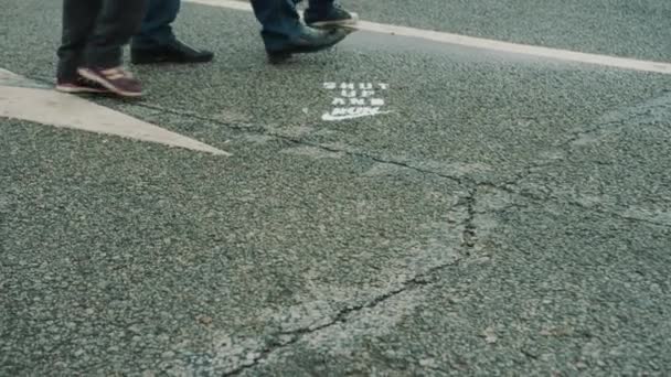 Piedi di persone che camminano su asfalto bagnato con segnaletica stradale — Video Stock