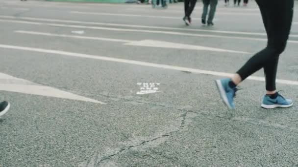 Piernas de personas caminando sobre asfalto húmedo con marca de carretera — Vídeos de Stock