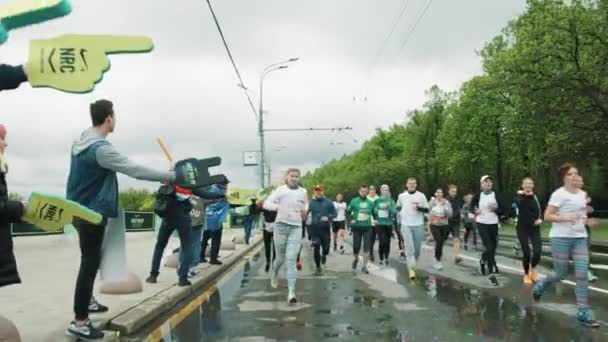 Толпа людей на тротуаре дает пять спортсменам, бегущим — стоковое видео