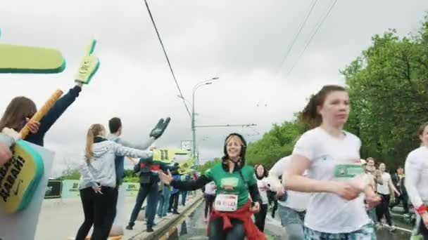 Vacker flicka jogger klappar skum händer på fans kör marathon — Stockvideo