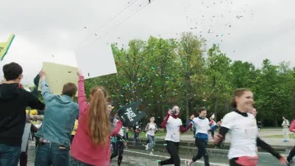 Толпа людей на тротуаре аплодирует спортсменам, бегущим маратом — стоковое видео