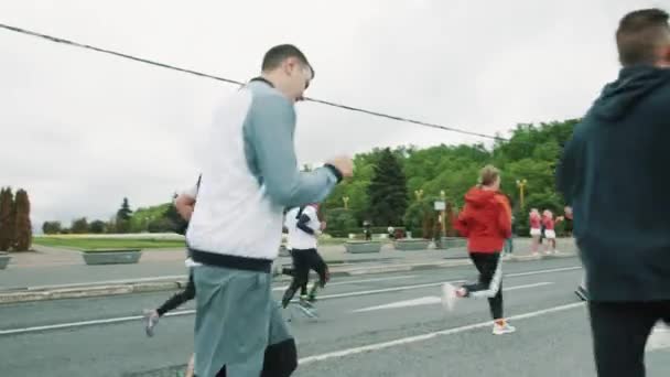 Barbudo corredor hombre corriendo maratón en multitud sosteniendo auriculares — Vídeos de Stock
