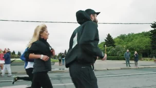 Homem atleta barbudo correndo maratona na multidão segurando fones de ouvido — Vídeo de Stock