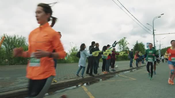 Menschen auf dem Bürgersteig jubeln Athleten zu, die Marathon laufen — Stockvideo