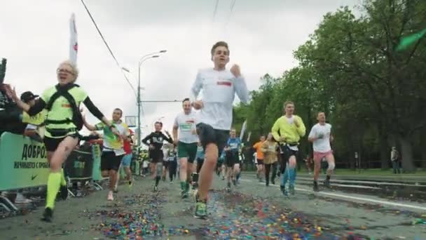 Atletas alegres corriendo maratón sobre asfalto húmedo cubierto de con — Vídeo de stock