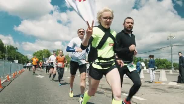 Wesoła dziewczyna w okulary pokazuje znak kawałek aparatu podczas runn — Wideo stockowe