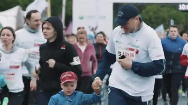 Hombre mantenga pequeño brazo de niño corriendo maratón con multitud de personas — Vídeo de stock