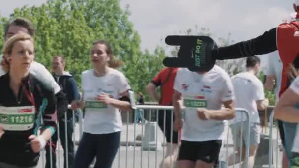 Cheering fan holding foam arm toward marathon running sportsmen — Stock Video
