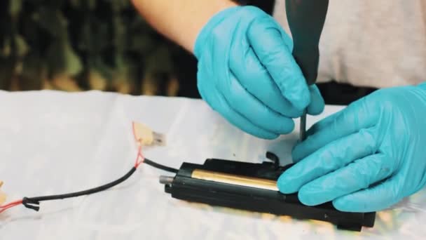 Master hands in blue rubber gloves detach trigger of glue gun with screwdriver — Stock Video