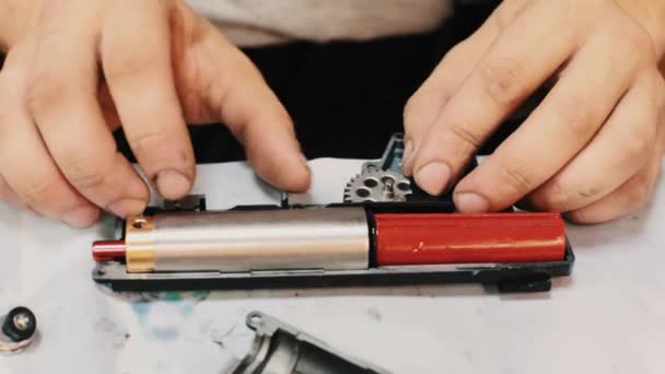 Робочі чоловічі руки складають механізм спуску зламаного гарячого клейового пістолета — стокове відео