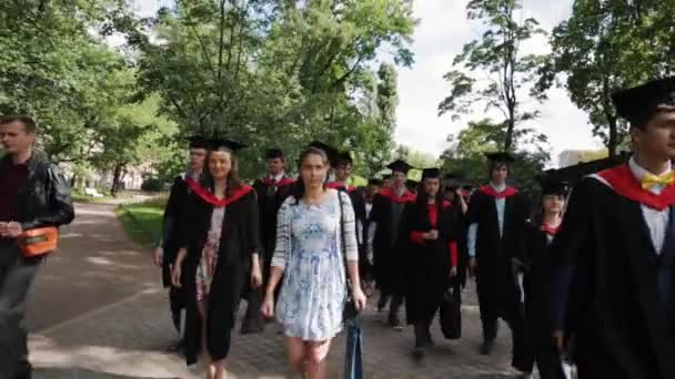 Multitud de estudiantes graduados caminando por el parque de la ciudad — Vídeo de stock