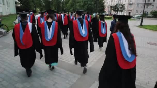 Grupo de estudiantes graduados caminando por la plaza de la ciudad — Vídeo de stock