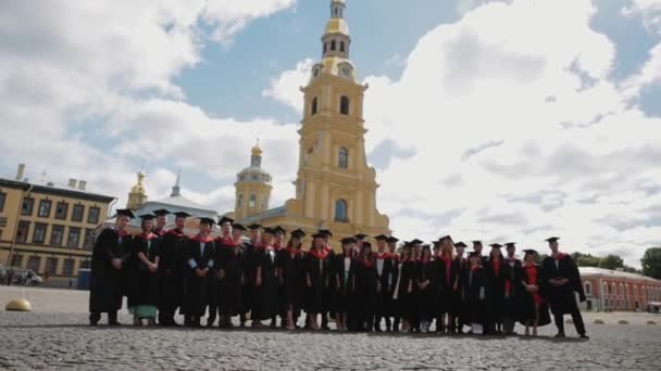 Grupo de estudiantes graduados de pie en la plaza de la ciudad — Vídeo de stock