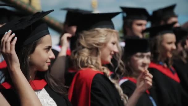 Группа жизнерадостных выпускников, позирующих для фото на открытом воздухе — стоковое видео
