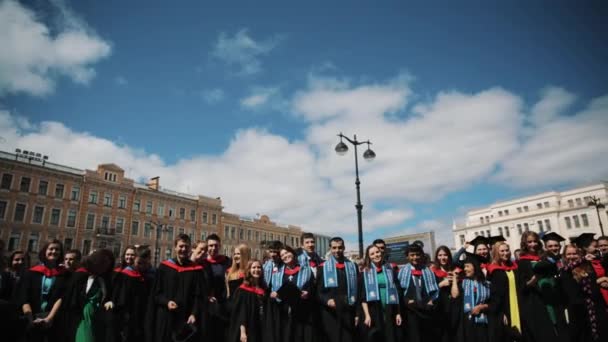 Grupo de estudantes de graduação joga tampas acadêmicas quadradas em ai — Vídeo de Stock