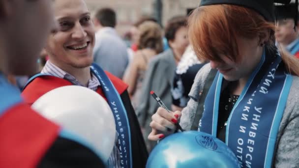Graduate flicka skriver önskemål med markör på ballong, det blåser — Stockvideo
